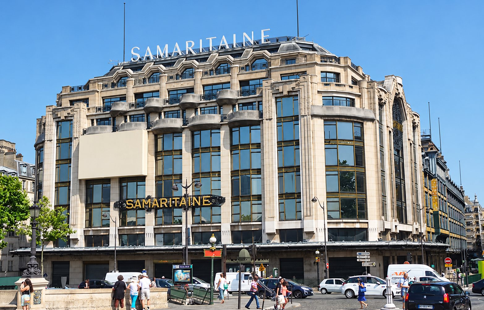 Vue extérieure de l'immeuble Art déco de la Samaritaine, dont le nom apparaît en lettres sur le toit et au-dessus de l'entrée, avec des passants et des véhicules au premier plan.
